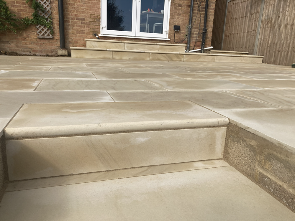Buff sandstone patio with bullnose steps and brick planters